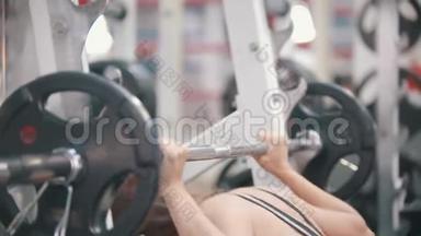 一位在健身房训练的女运动员放下哑铃，擦去额头上的汗